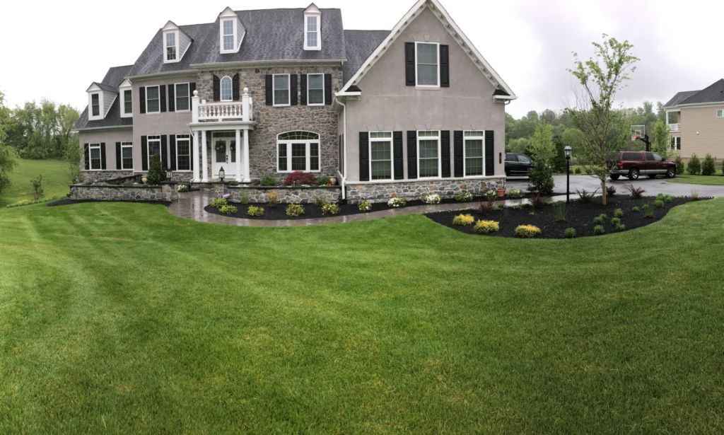 Manicured lawn and landscaped beds in front of a stone home