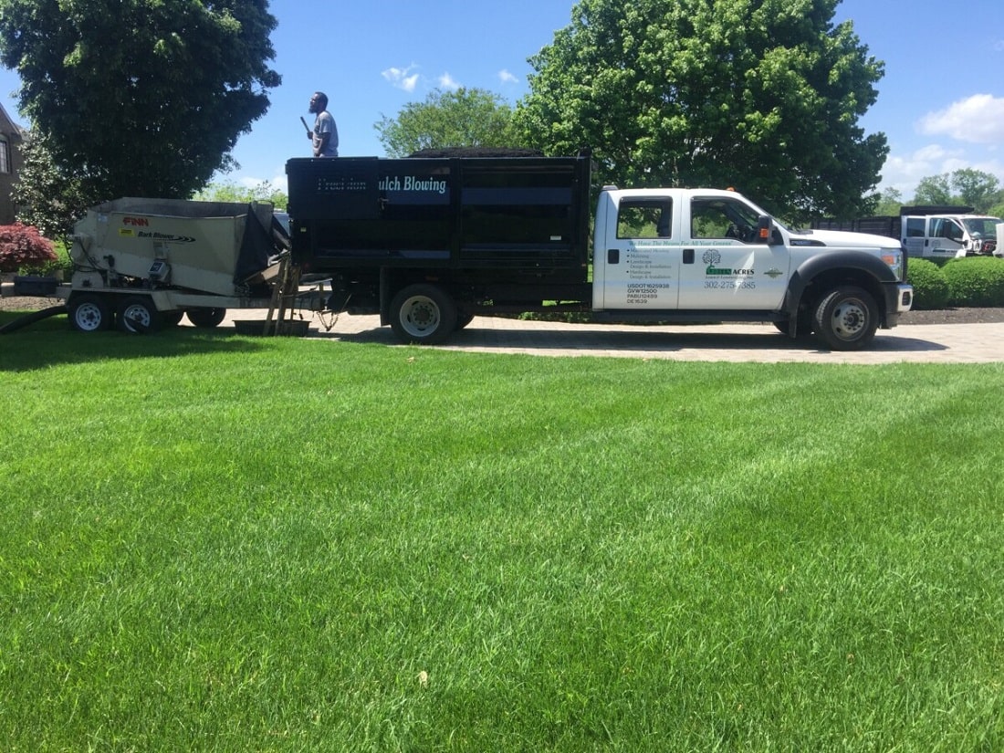 Lush green lawn maintained by Green Acres with company truck in the background