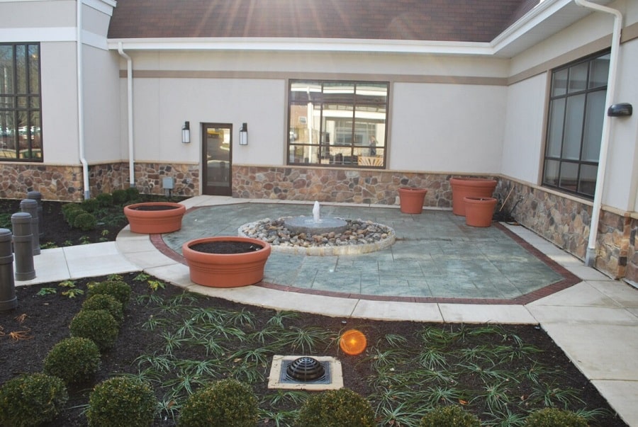 Installed commercial landscape with a water feature and layered planting beds
