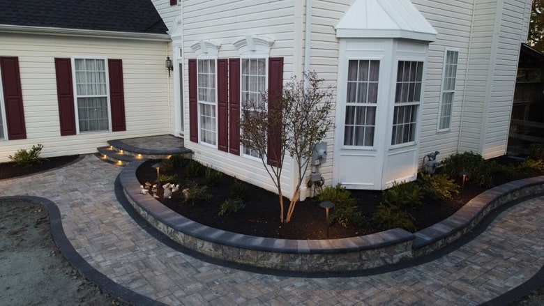 Paver walkway wrapping around a residential home with landscape lighting
