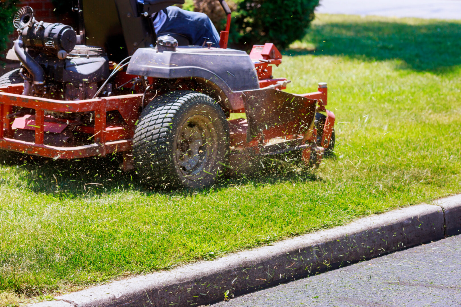 Commercial red zero-turn mower cutting a green lawn during professional lawn maintenance